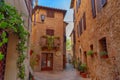 Pienza, Italy Ã¢â¬â May 27, 2017: Beautiful narrow street with sunlight and flowers in the village of Pienza, Italy Royalty Free Stock Photo